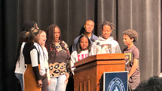 PHOTO BY MARÍA CAMP - Aaron Freeman directs Russellville Middle School Students in singing the national anthem as part of the annual Russellville City Schools Black History Month program.  